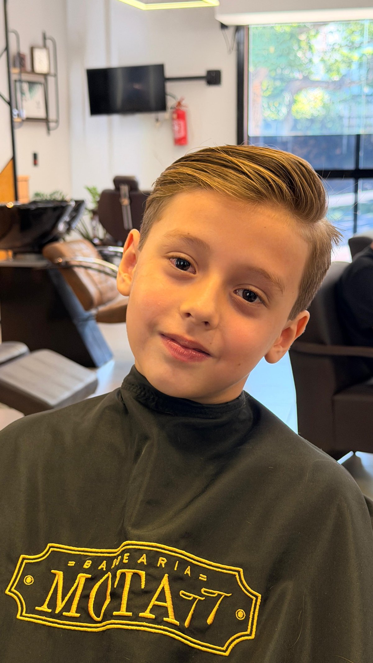 Criança sorrindo após o corte na Barbearia Mota77